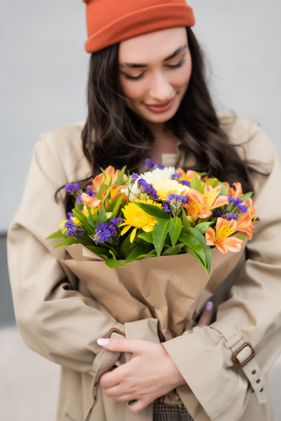 selektiver Fokus der trendigen Frau beim Betrachten eines Blumenstraußes  - Foto, Bild