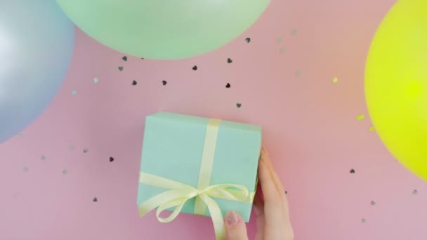 Unrecognizable woman with Christmas birthday gift box wrapped in green paper on pink background top view - Footage, Video