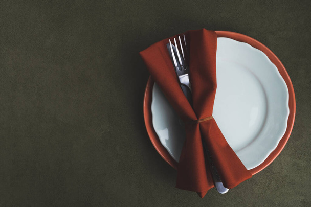 Autumn Thanksgiving setting table. Plates, fork, knife with serving napkin on dark green tablecloth. Vintage style. Top view, flat lay, copy space - Photo, Image
