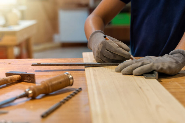 Young carpenter measuring the wood with ruler. Selective focus - 写真・画像