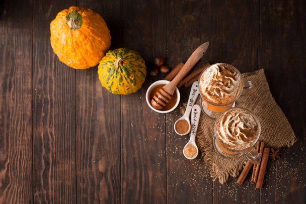 Pumpkin spice latte with whipped cream on top on rustic wooden background. Selective focus. Holiday autumn concept - Photo, Image