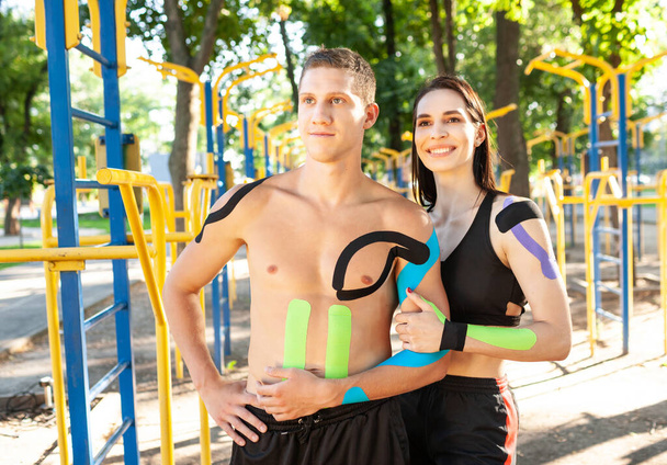 Sports couple with kinesiology taping posing outdoors. - Foto, Imagen