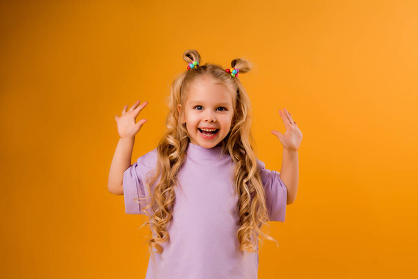 Cute little cheerful girl isolated on orange background, children 's emotions concept. - Фото, изображение