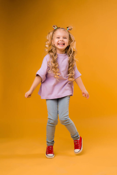 Carino piccola ragazza allegra isolata su sfondo arancione, concetto di emozioni dei bambini. - Foto, immagini