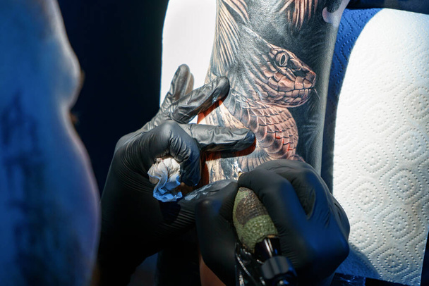 Foto di maestro che fa il tatuaggio nero di serpente per donna - Foto, immagini