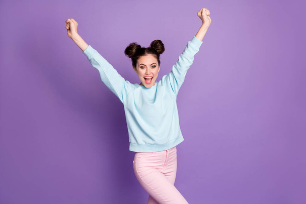 Portrait of delighted girl youth enjoy corona virus lucky win raise fists shout yeah wear good look trousers isolated over violet color background - Foto, afbeelding