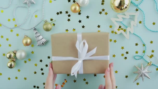 Caja de regalo de Navidad en manos de mujer sobre fondo azul vista superior - Metraje, vídeo