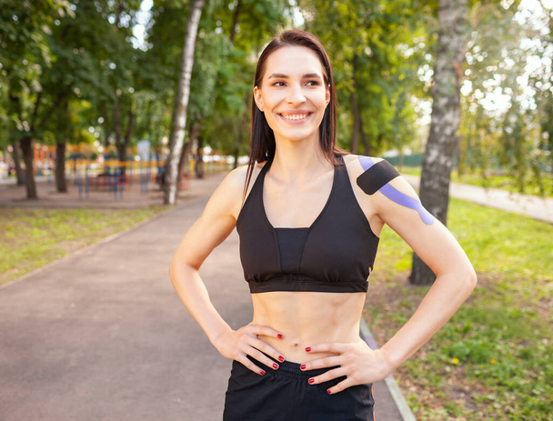 Fit woman with kinesiological taping posing outdoors. - Valokuva, kuva