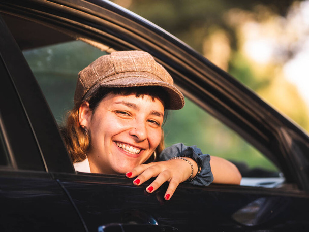 Ein Bild einer brünetten Frau in einem schwarzen Auto mit einem erstaunlichen Lächeln - Foto, Bild
