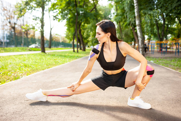 Flexible woman with kinesiology taping practicing lunges outdoors. - Foto, Imagem