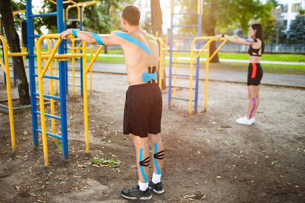 Couple with kinesiological elastic taping training at sports ground. - Фото, зображення