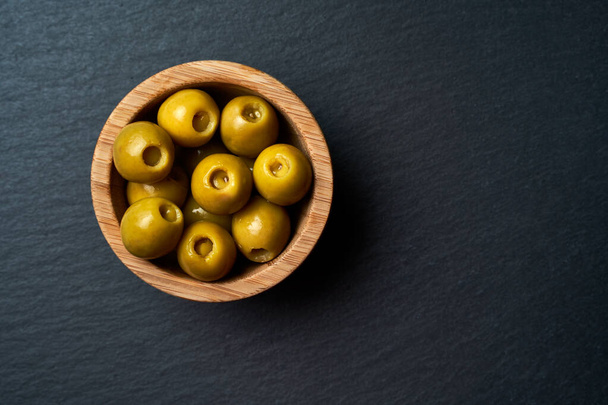 Ciotola di legno con olive su sfondo scuro. - Foto, immagini