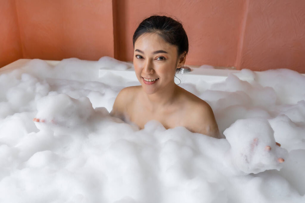young woman relaxing and takes bubble bath in bathtub with foam - Foto, afbeelding