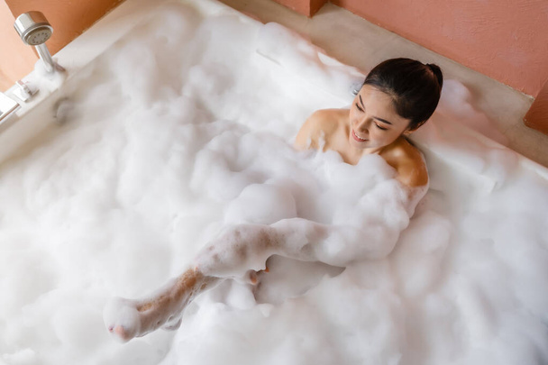 young woman relaxing and takes bubble bath in bathtub with foam - Fotografie, Obrázek