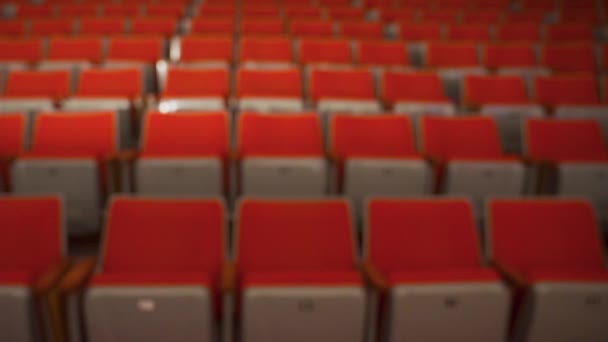 Filas vacías de asientos de cine. Medios. Vista borrosa de los asientos rojos vacíos en la sala de cine. salas de cine vacías debido a la pandemia de coronavirus - Imágenes, Vídeo