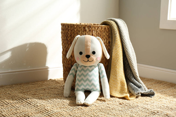 Cute toy dog and basket with plaid indoors. Baby room interior elements - Foto, Bild