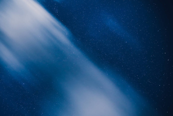 Vista horizontal de un cielo azul nocturno con estrellas en el campo. Vía Láctea bajo las nubes. - Foto, imagen