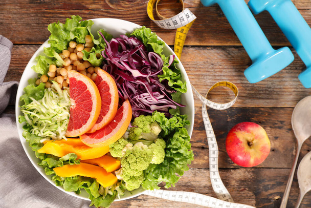 health food- diet food concept with vegetable salad and dumbbell - Foto, Imagem