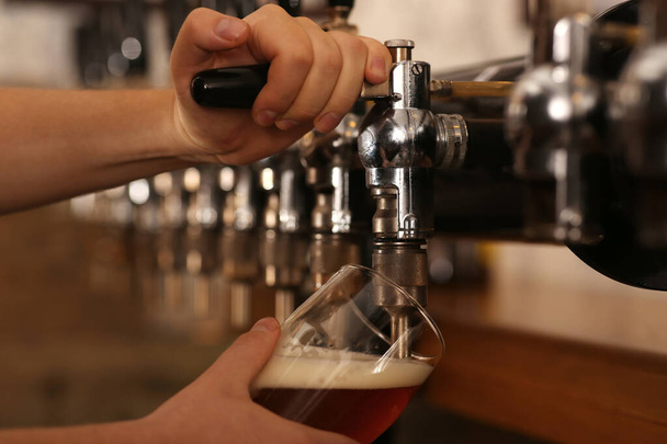 Bartender pouring fresh beer into glass in pub, closeup - Foto, Bild