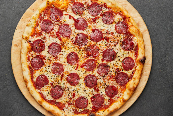 Delicious Italian Pizza pepperoni with mozzarella cheese and salami on dark background - Zdjęcie, obraz