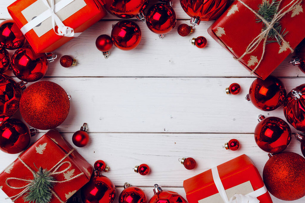 Packed small Christmas gifts and red baubles on white wooden board - 写真・画像