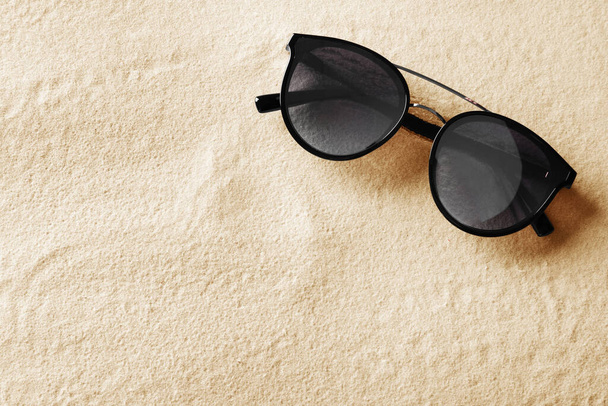 Stylish sunglasses on white sand, top view. Space for text - Zdjęcie, obraz