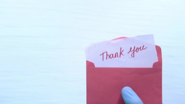 mano en guantes protectores sosteniendo mensaje de agradecimiento  - Imágenes, Vídeo
