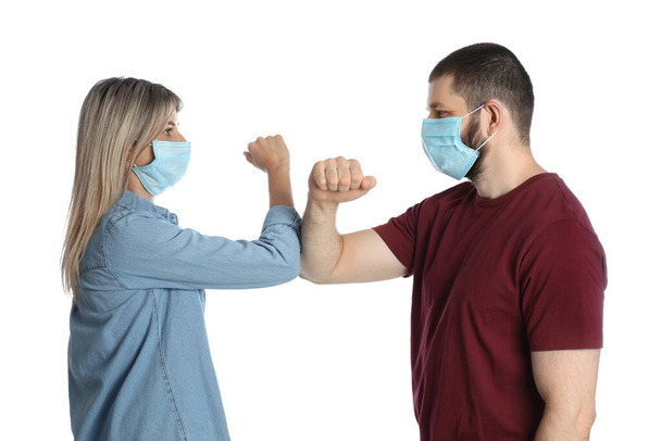 Man and woman bumping elbows to say hello on white background. Keeping social distance during coronavirus pandemic - Фото, изображение