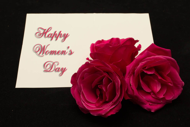 Feliz Día de la Mujer 8 de marzo escrito en tarjeta blanca con rosas rojas - Foto, imagen