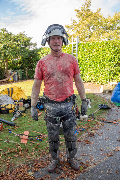 Arborist or Tree Surgeon wearing safety equipment covered in sawdust. - Photo, Image