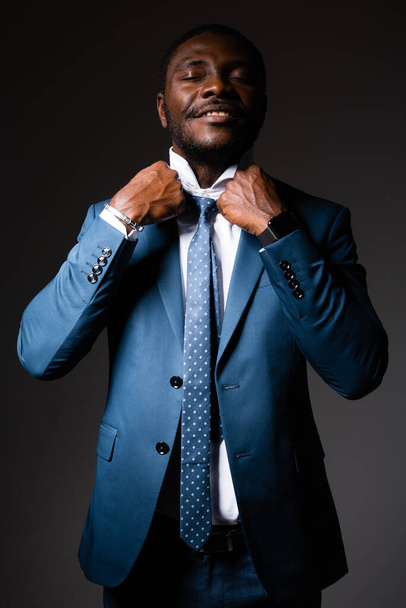 Portrait of an African American man in a blue business suit, who straightens the collar of his shirt - Foto, Imagen
