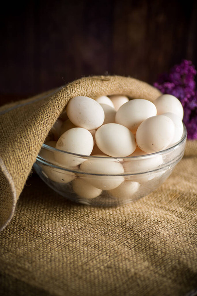 huevos frescos hechos en casa orgánicos en un tazón de vidrio debajo de la arpillera en una mesa de madera
 - Foto, imagen