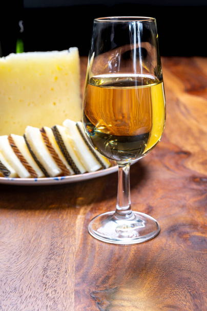 Ισπανικό fino dry sherry κρασί από την Ανδαλουσία και κομμάτια από διάφορα σκληρά τυριά manchego προβάτων που παρασκευάζονται στη La Mancha, Ισπανία. Συνδυασμός κρασιού και τυριού - Φωτογραφία, εικόνα