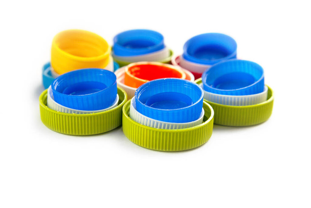 Composition of plastic caps on a white background. Top view of recycled plastic bottle caps. Separate garbage collection. Recycling of plastic for prosthetics. Selective focus.  - Photo, Image