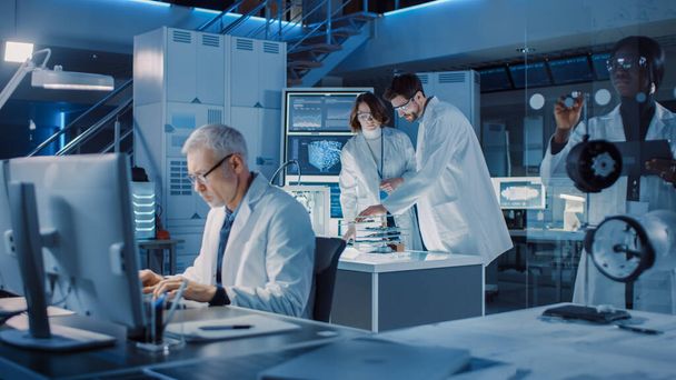 Diverse International Team of Industrial Scientists and Engineers Wearing White Coats Working on Heavy Machinery Design in Research Laboratory. Professionals Using Computers and Talking - Photo, image