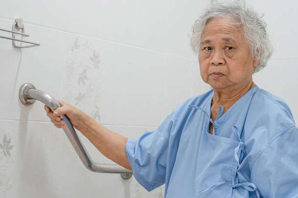 Ασιάτισσα ηλικιωμένη ή ηλικιωμένη ηλικιωμένη γυναίκα ασθενής χρήση τουαλέτα χειριστεί την ασφάλεια στο θάλαμο νοσηλευτικό νοσοκομείο, υγιή ισχυρή ιατρική έννοια. - Φωτογραφία, εικόνα