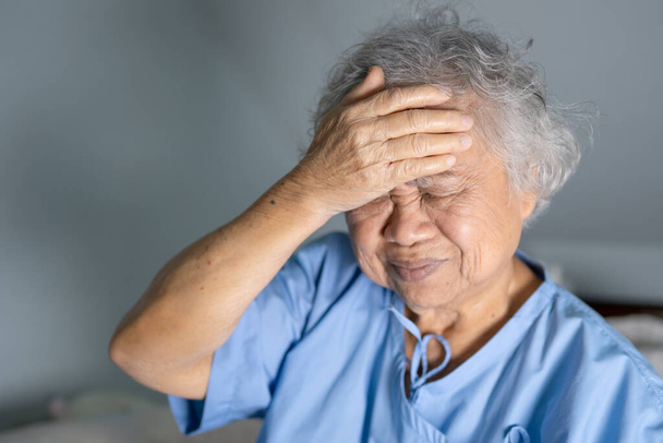 Asiática senior o anciana anciana mujer anciana paciente dolor de cabeza mientras está sentado en la cama en enfermería hospital sala, saludable fuerte concepto médico - Foto, imagen
