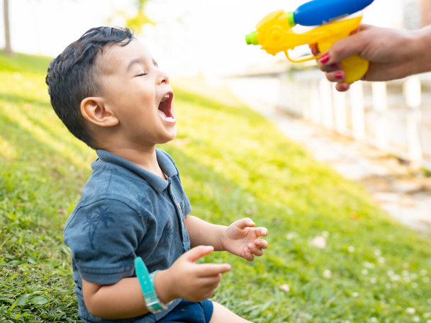 happy little boy playing with a squirt gun, with his mom - Фото, зображення