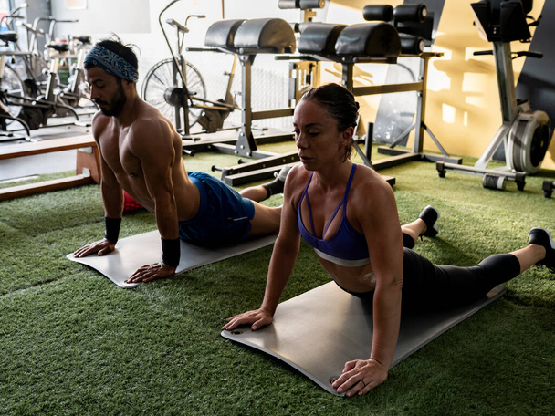 mężczyzna i kobieta w siłowni robi mięśnie brzucha - Zdjęcie, obraz