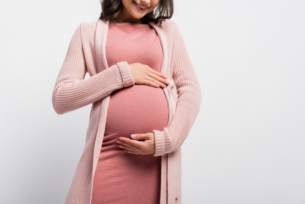 oříznutý pohled radostné těhotné ženy dotýkající se břicha izolované na bílém - Fotografie, Obrázek
