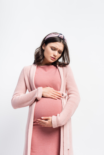 λυπημένη έγκυος γυναίκα στο κεφαλόδεσμο αγγίζοντας την κοιλιά απομονώνονται σε λευκό - Φωτογραφία, εικόνα