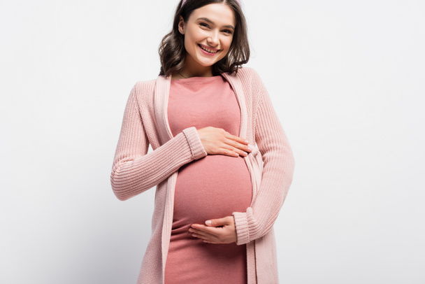 joyful pregnant woman touching belly on white - Foto, afbeelding