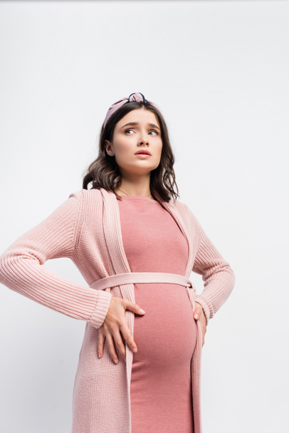 mujer embarazada preocupada en diadema tocando el vientre y mirando hacia otro lado aislado en blanco - Foto, Imagen