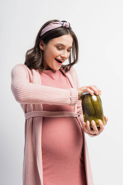 ενθουσιασμένοι και έγκυος γυναίκα άνοιγμα βάζο με αγγούρια τουρσί απομονώνονται σε λευκό - Φωτογραφία, εικόνα