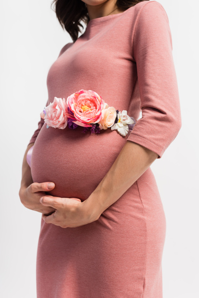 Teilansicht einer schwangeren Frau mit geblümtem Gürtel, die isoliert auf weiß steht  - Foto, Bild