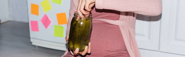 website header of pregnant woman holding canned jar with cucumbers at home - Foto, afbeelding