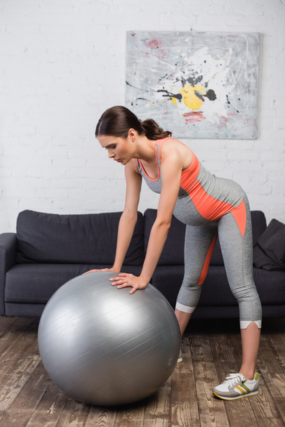 brunette pregnant woman working out with fitness ball in living room  - Valokuva, kuva