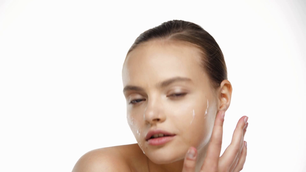 Retrato de mujer joven aplicando crema en la cara aislada en blanco - Metraje, vídeo