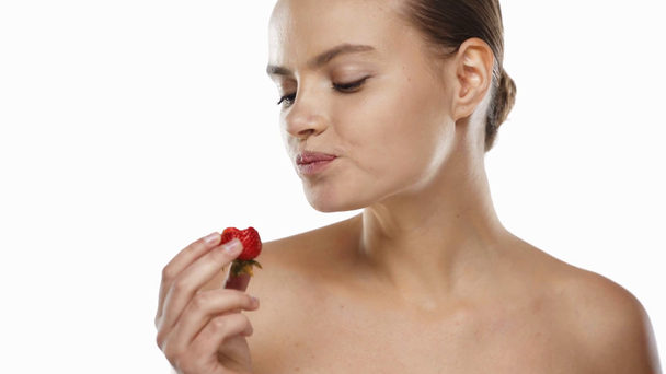 Mladá žena čichá a jí jahody izolované na bílém - Záběry, video