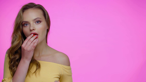 młoda kobieta korzystających jedzenie truskawki izolowane na różowy - Materiał filmowy, wideo